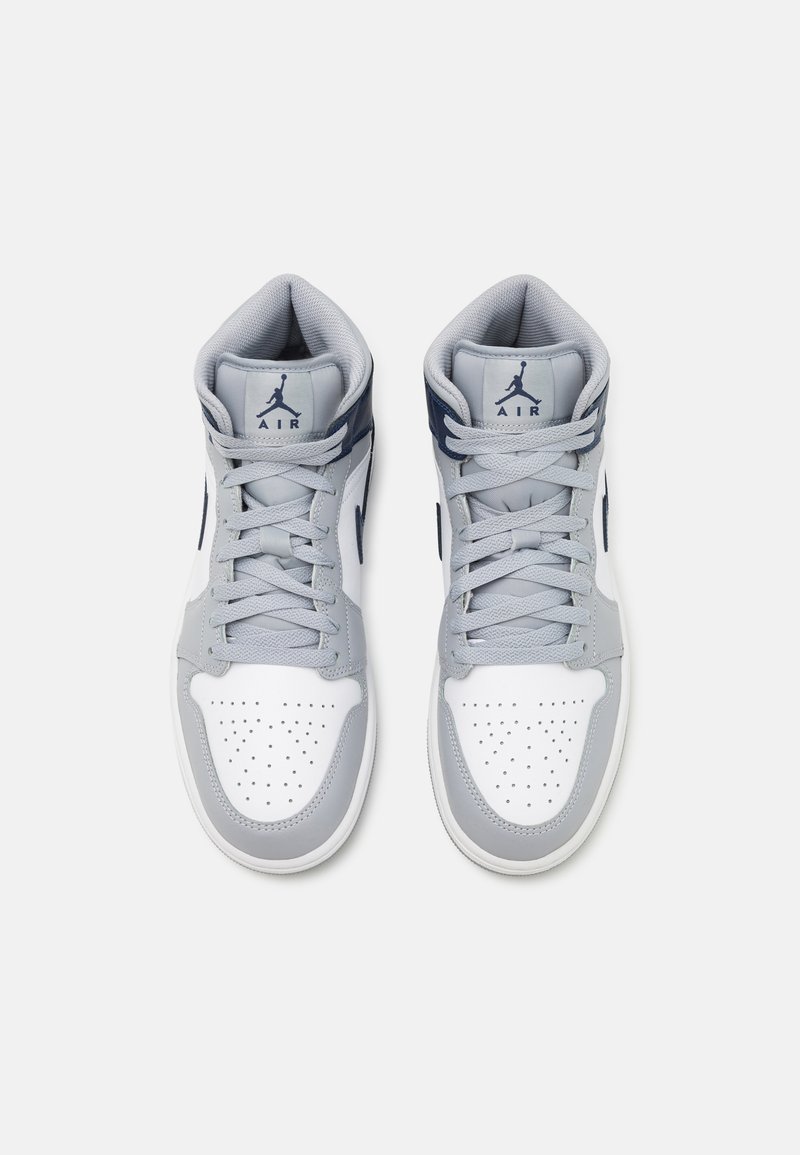 Zapatillas altas con parte superior de cuero en gris claro y blanco, con detalles en azul marino, puntera perforada y cordones.
