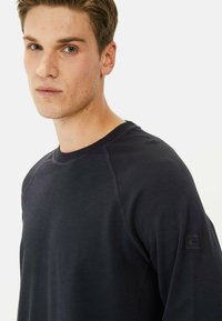 Donker marineblauwe crewneck sweatshirt, vervaardigd uit een zachte, gestructureerde stof. Heeft raglanmouwen en een klein logovoorziening op de linkermouw.