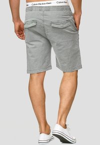 Gray cotton shorts with a relaxed fit, featuring two back pockets and a branded waistband. Finished with contrast stitching and rolled hems.