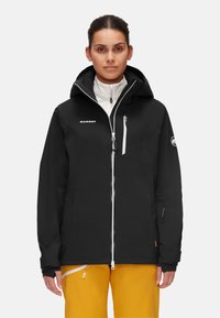 Svart vattentät jacka med huva, främre dragkedja och flera fickor. Har justerbara ärmslut och en logotyp på bröstet.