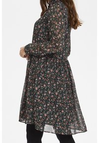 Czarna sukienka w kwiaty z długimi rękawami, zebrana w pasie, z przezroczystego materiału i długości powyżej kolana. Wzór zawiera kolorowe kwiaty.