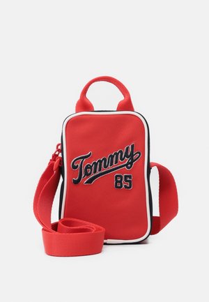 Petit sac bandoulière rouge avec poignée, sangle réglable, bordure blanche et texte brodé "Tommy 85" à l'avant.