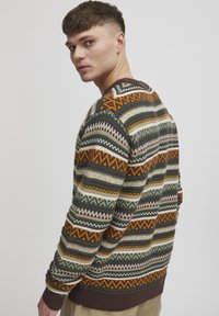 Stickad tröja med flerfärgade zigzag- och horisontella mönster i grön, brun, orange och kräm; rund halsringning; ribbade muddar och nederkant.