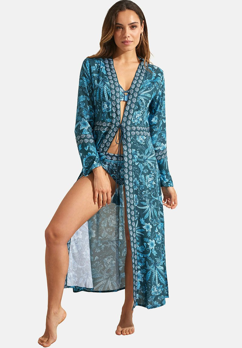 Lange, teal kimono met bloemenpatronen, voorzien van lange mouwen, een diepe V-hals en een strikdetail op de taille, gemaakt van lichte stof.