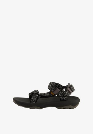Black sandal with patterned straps and a textured sole. Features adjustable straps and a contoured footbed for support.