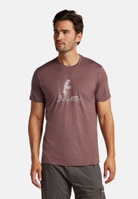 Camiseta de manga corta color marrón oscuro, hecha de un material ligero, con un gráfico de un oso y equipo de pesca en la parte frontal.