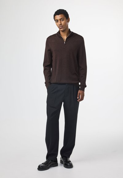 Brauner Zip-Pullover mit langen Ärmeln, kombiniert mit schwarzen Hosen und schwarzen Halbschuhen. Glatte Textur und gerades Design.