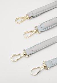 Szare paski z imitacji skóry z metalowymi klipsami w kolorze złotym. Gładka faktura, minimalistyczny design i jednolita szerokość na całej długości. Widać trzy paski.