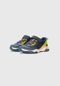 Blaue und schwarze Sportschuhe mit einem Klettverschlussriemen, bunten Schnürsenkeln und strukturierten Sohlen. Besitzt lebendige Akzente in Gelb und Orange.