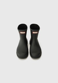 Black rubber ankle boots with a smooth texture, featuring a branded red and white label at the front. No visible patterns or accents.