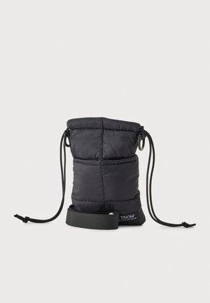 Bolsa negra acolchada con cierre de cordón y cordones largos, anillas metálicas, un bolsillo delantero y una correa con la marca, sobre un fondo liso.