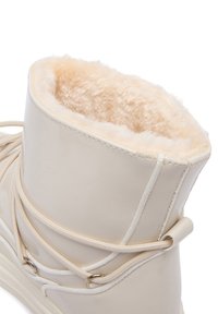 Botă impermeabilă bej cu căptușeală din blană sintetică, vârf rotund și detalii cu șireturi. Material exterior neted și căptușeală texturată pentru căldură.