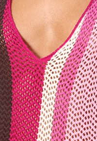 Strikket topp med V-halsdesign i en blanding av farger: mørkebrun, rosa, lys rosa og kremfarge, med en åpen vevstruktur.