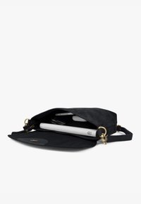 Schwarze Leder-Crossbody-Tasche, geöffnet und zeigt ein weißes Tablet, ein Smartphone und Schlüssel darin vor einem schlichten weißen Hintergrund.