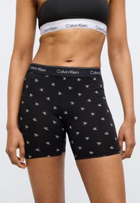 Μαύρα βαμβακερά μποξεράκια με εφαρμοστή σχεδίαση. Διαθέτουν μικρά επαναλαμβανόμενα λογότυπα CK σε πιο ανοιχτή απόχρωση, συνοδευόμενα από μαύρη μέση με λογότυπο.