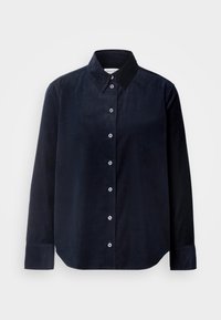 Chemise noire à manches longues avec col, sept boutons blancs sur le devant et poignets boutonnés.
