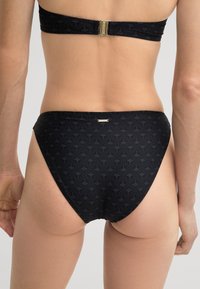 Schwarzer Bikiniunterteil mit einem dezenten Muster und goldenen Hardware-Details. Verfügt über eine glatte Textur und ein klassisches, niedrig geschnittenes Design.