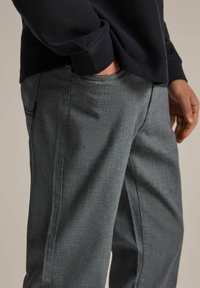 Szare, teksturowane spodnie w prostym kroju, z bocznymi kieszeniami i subtelnymi detalami szwów, w komplecie z granatową bluzką z długim rękawem.