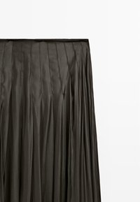 Černá skládací sukně vyrobená z hladkého, lesklého materiálu s vertikálními švy, s drapeným designem, který sahá až k zemi.