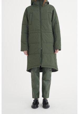 Long green puffer coat with a hood, featuring two horizontal chest pockets, vertical seams, and a zip closure. Worn over matching green leather pants.