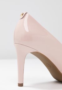 Talons aiguilles roses en vernis avec un bout pointu, un design épuré et un accent doré près de l'arrière. Comprend un talon aiguille fin et une texture lisse.