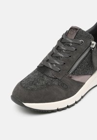 Šedá sportovní bota vyrobená z kombinace semiše a filcu, s kovovými akcenty, šněrováním a bočním zipem.