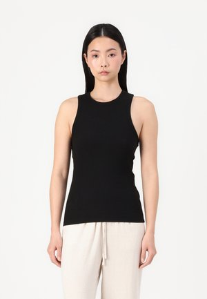 Schwarz geripptes Tanktop mit taillierter Passform, rundem Ausschnitt und breiten Schulterträgern, kombiniert mit hellen Leinenhosen mit Kordelzug.
