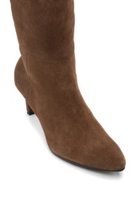 Brun mockakänga i mid-calf höjd med spetsig tå och låg kittenklack, visad mot en vit bakgrund.