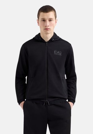 Black zip-up hoodie made of soft fabric, featuring a front logo, kangaroo pockets, and a drawstring hood with textured detailing on sleeves.