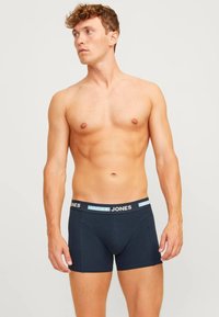 Marineblauwe boxer shorts met een aansluitend ontwerp, voorzien van een logo-banden in blauw en zwart. Zacht materiaal en een gladde textuur.