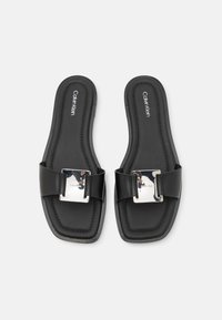 Svarta platta sandaler med kvadratisk tådesign, med ett brett rem och en metallspänneaccent. Slät läderstruktur med logodetalj.