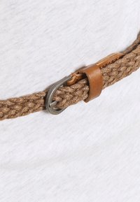 Brązowy pleciony pasek z tkaniny z metalową klamrą i brązowymi skórzanymi akcentami, zaprezentowany na jasnoszarym tle.