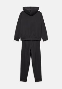 Survêtement noir en tissu lisse et léger. Comprend une veste à capuche avec des poignets côtelés et un pantalon assorti à taille élastique.