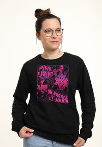 Felpa nera con una grafica colorata raffigurante elefanti rosa e il testo "Elefanti Rosa in Parata". Tessuto morbido, maniche lunghe, vestibilità rilassata.