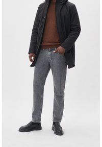 Manteau isolant noir, pull marron, jean gris à jambe droite, et chaussures noires slip-on. Design minimaliste, couleurs unies, et coupe décontractée.