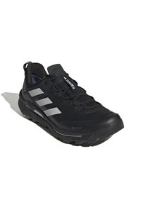 Czarny but sportowy z teksturowaną siateczką z góry, gumową podeszwą i odblaskowymi srebrnymi akcentami. Posiada metkę GORE-TEX, co zapewnia wodoodporność.