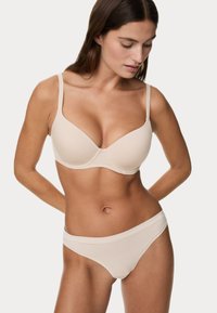 Soutien-gorge beige en tissu lisse, avec armatures et bretelles réglables, associé à un bas de bikini beige assorti. Les deux présentent des bords élastiques doux.