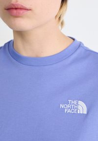 Gaiši violetas krāsas kokvilnas T-krekls ar apaļu kakla izgriezumu, uz kreisā krūšu laukuma ir balts izšūts logo "The North Face".