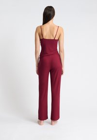 Burgundy tvådelad lounge-outfit som innehåller en figurnära linne med tunna band och vida byxor med ribbad struktur och rå kant.