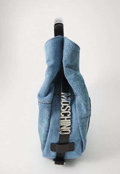 Sinine denim seljakott kortsus ülaosaga, millel on läikiv hõbedane "Moschino" logo, mustad nahast detailid ja tekstuuriline viimistlus.