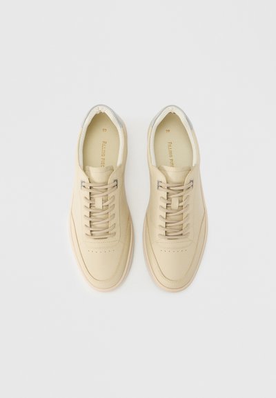 Beezhast nahast spordijalatsite paar, millel on paelad, hallid silmad ja polsterdatud kraed, vaadatuna ülalt valgel taustal.