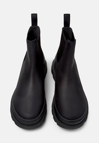Bottines noires en cuir avec des panneaux élastiques sur les côtés, des tirettes à l'arrière et une semelle en caoutchouc. Texture lisse et design à bout arrondi.