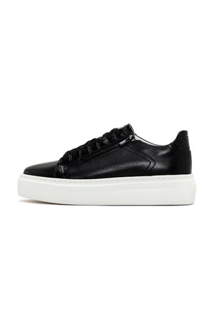 Sneaker en cuir noir avec un design texturé, doté d'une semelle plateforme blanche, d'une fermeture éclair décorative et de lacets.
