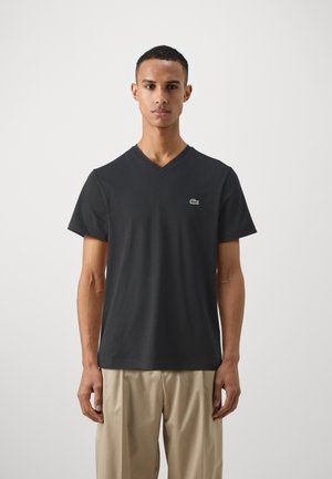 Mørkegrå kortærmet V-hals t-shirt lavet af bomuld, med et lille grønt logo på venstre bryst. Enkel, klassisk skæring og glat tekstur.