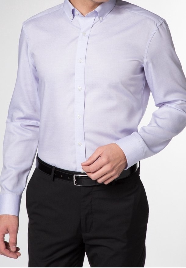 Chemise boutonnée violet clair avec col, manches longues et texture lisse, associée à un pantalon noir et une ceinture noire.