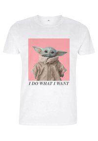 Biała koszulka z grafiką postaci w beżowej kurtce z wysokim kołnierzem, na różowym tle, z tekstem poniżej.