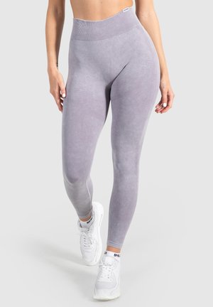 Lila hoge taille leggings met een zachte, gestructureerde oppervlakte en een geribde tailleband, gecombineerd met witte sport sneakers.