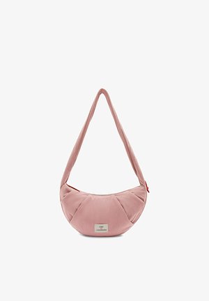 Sac d'épaule rose pâle en forme de croissant avec une sangle large et une petite étiquette blanche indiquant "UNIO x VISIONNAIRES" à l'avant.