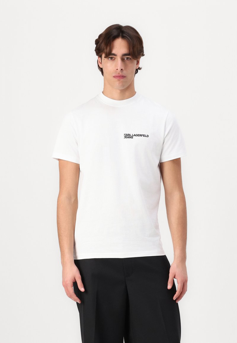Weißes Baumwoll-T-Shirt mit Rundhalsausschnitt und kurzen Ärmeln. Schwarzes "KARL LAGERFELD JEANS"-Logo auf der oberen linken Seite.