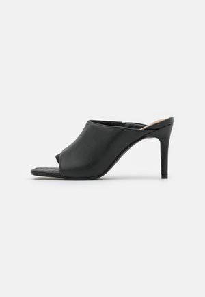 Sort åben-toe mule med glat overdel, tynd høj hæl og slip-on design vist fra siden på en hvid baggrund.